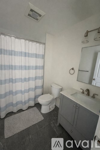 A bathroom with a toilet, sink, and shower curtain.
