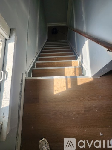 A person's foot is visible on a wooden staircase.