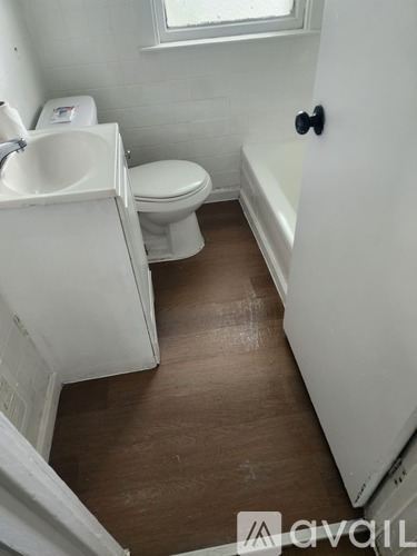 A white toilet sits next to a white sink in a small bathroom.