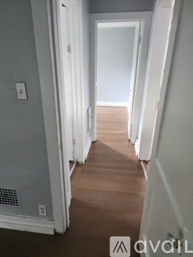 A hallway with white doors and a wooden floor.