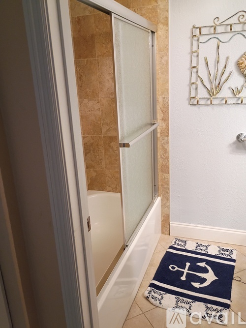 A bathroom with a blue and white rug on the floor.
