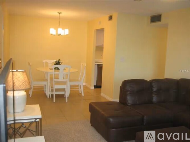 A living room with a white dining table and chairs, a brown leather couch, and a television.
