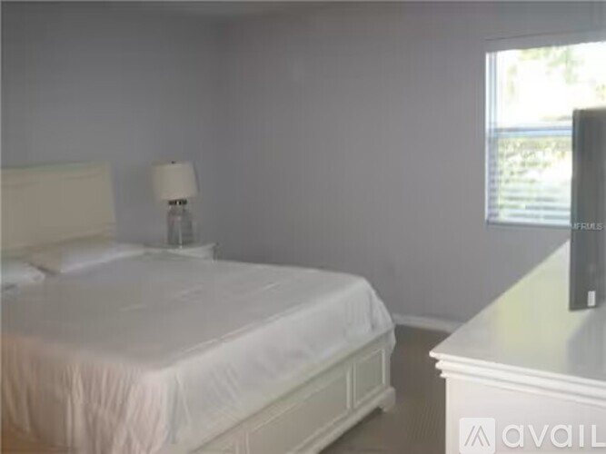 A bedroom with a white bed and a white nightstand.