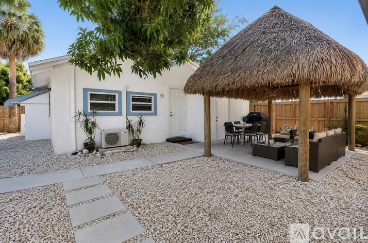 A white house with a thatched roof and a patio area.
