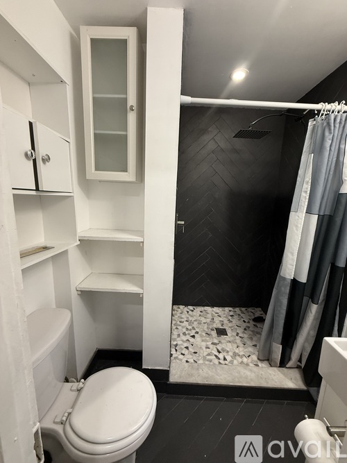 A small white bathroom with a toilet, a shower, and a cabinet.