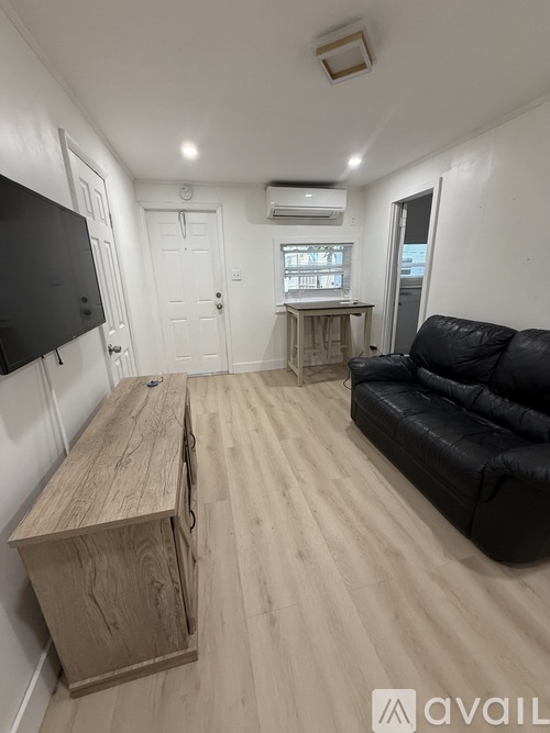 A living room with a black couch and a wooden cabinet.