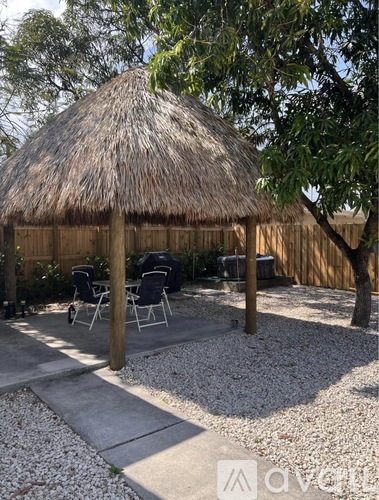 A small thatched hut with a concrete walkway leading to it.