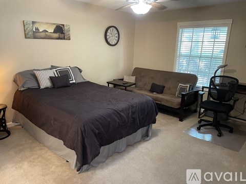 A bedroom with a bed, a couch, and a chair.