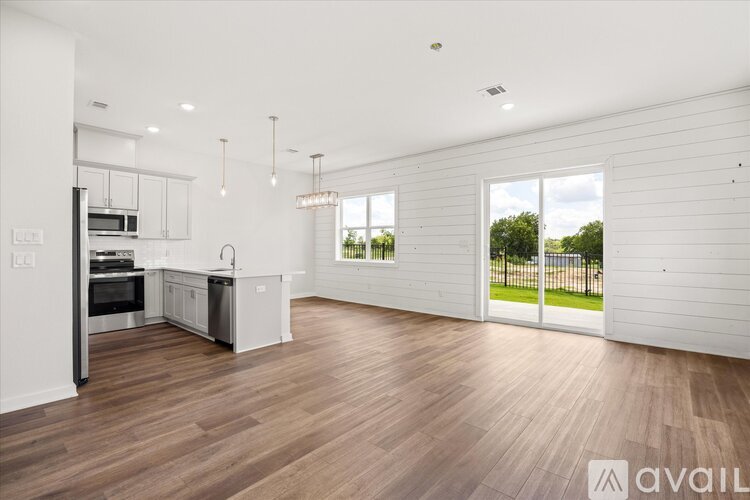 A spacious kitchen and living room with wooden flooring and white walls.