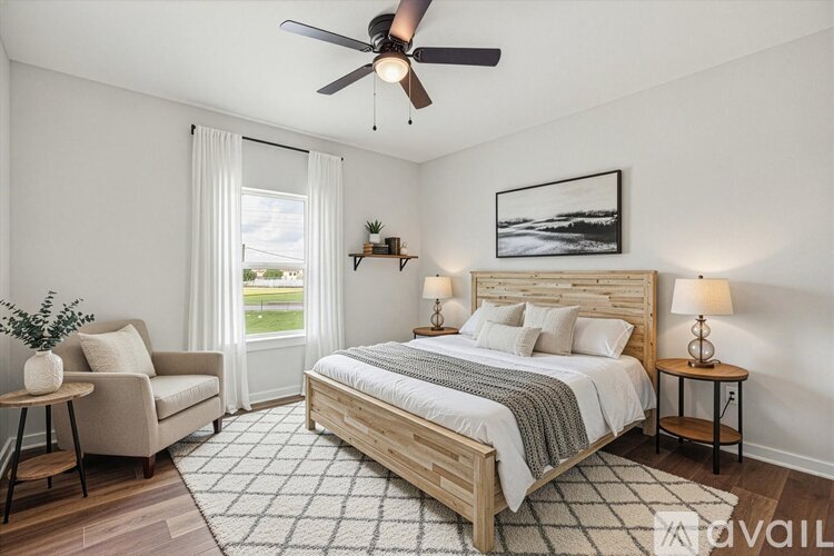 A bedroom with a large bed, a chair, and a ceiling fan.