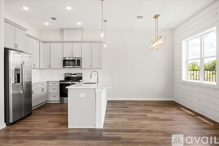A kitchen with white cabinets and a wooden floor.