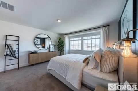 A well-lit bedroom with a large bed and a mirror on the wall.