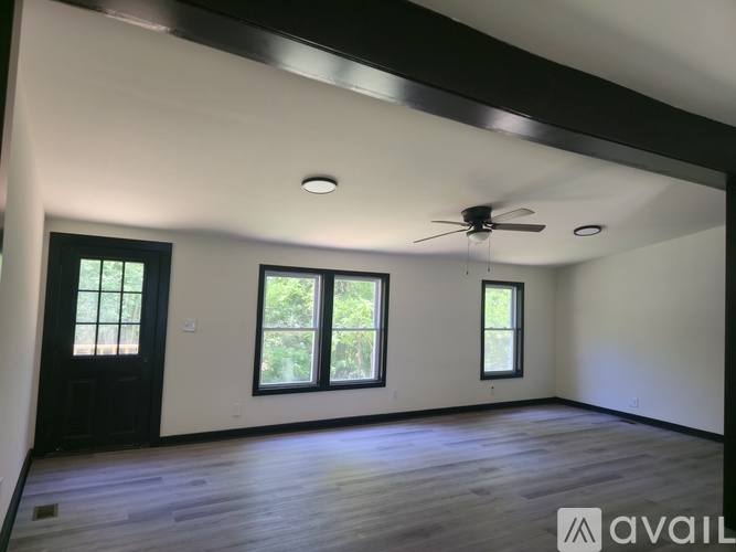 A spacious room with a ceiling fan and three windows.