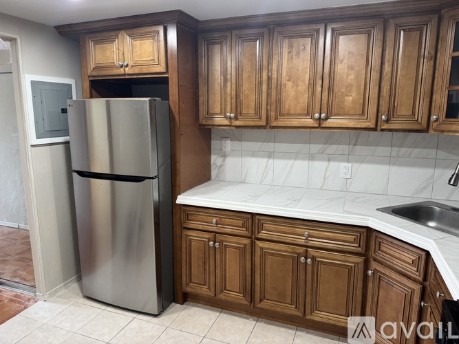 A kitchen with wooden cabinets and a stainless steel refrigerator.