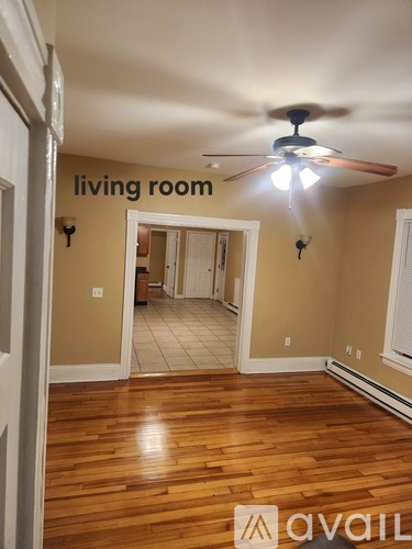 A living room with a ceiling fan and a doorway leading to another room.