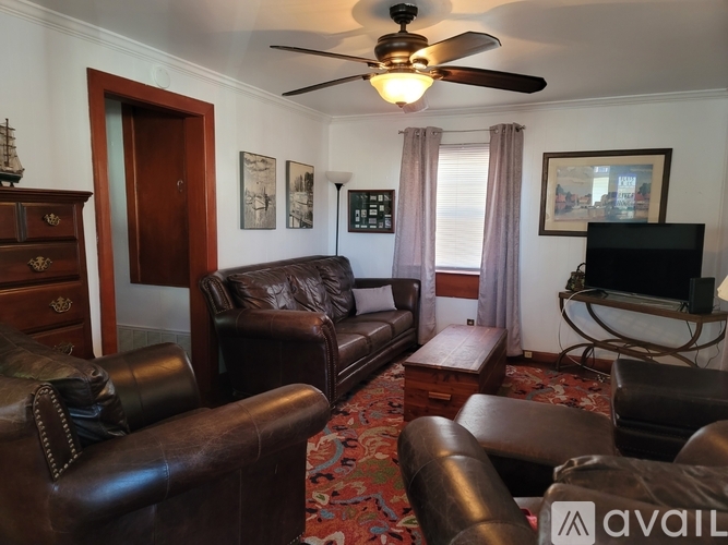 A living room with a brown leather couch and a television.