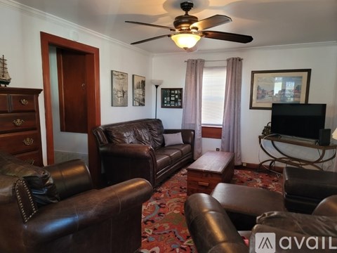 A living room with a brown leather couch and a television.