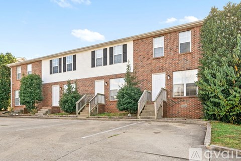 A brick apartment building with a parking lot in front.