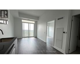 A spacious, empty room with a large window and sliding glass doors leading to a balcony.
