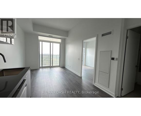A spacious, empty room with a large window and sliding glass doors leading to a balcony.