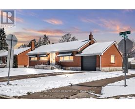 A house with a snow-covered roof and a street sign in front of it.