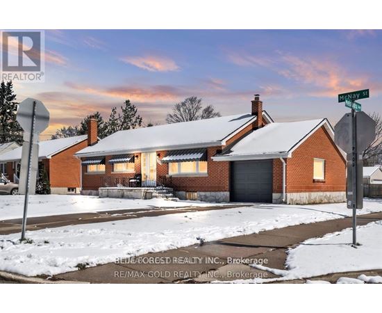 A house with a snow-covered roof and a street sign in front of it.
