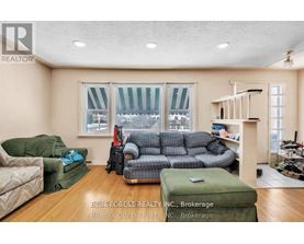 A living room with a couch, chair, ottoman, and a window with a view of the snow.