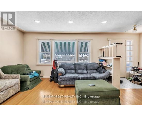A living room with a couch, chair, ottoman, and a window with a view of the snow.