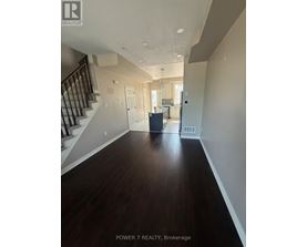 A spacious hallway with wood flooring and a staircase.