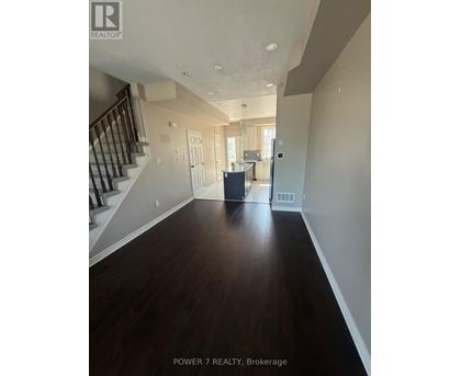 A spacious hallway with wood flooring and a staircase.