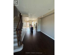 A spacious hallway with a staircase on the left and a doorway leading to another room on the right.
