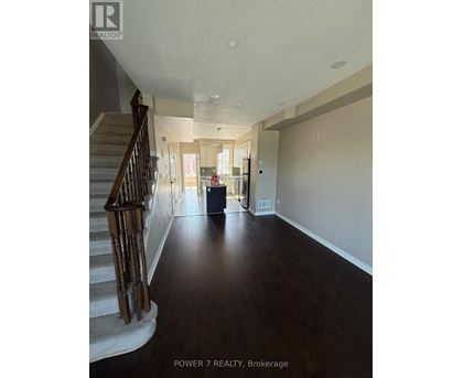 A spacious hallway with a staircase on the left and a doorway leading to another room on the right.