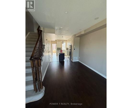 A spacious hallway with a staircase on the left and a doorway leading to another room on the right.