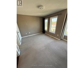 A room with carpeted floor and a window with a view of a building.