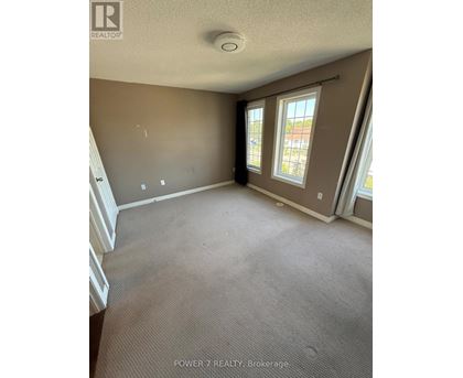 A room with carpeted floor and a window with a view of a building.