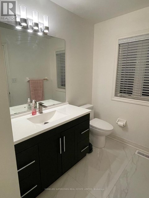 A bathroom with a sink, toilet, and a mirror.