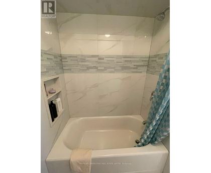 A white bathtub with a towel and a shower curtain.