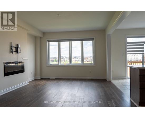 A spacious room with a large window and wooden flooring.