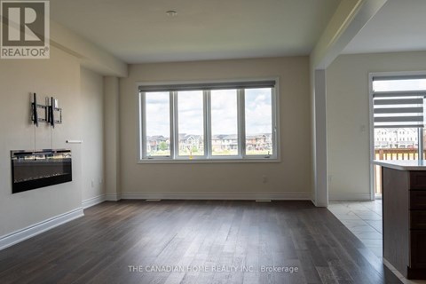 A spacious room with a large window and wooden flooring.