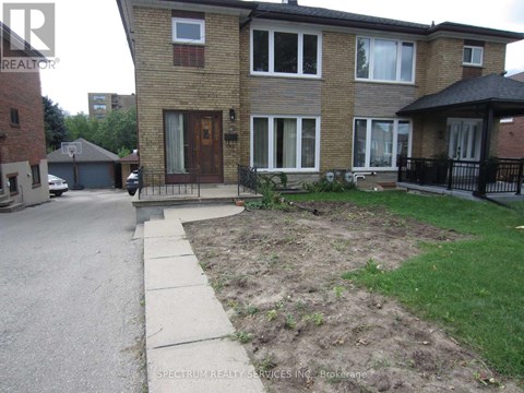 A brick house with a brown door and a small front yard.