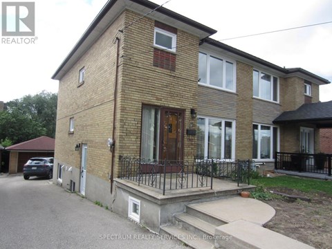 A brick house with a black iron fence in front.