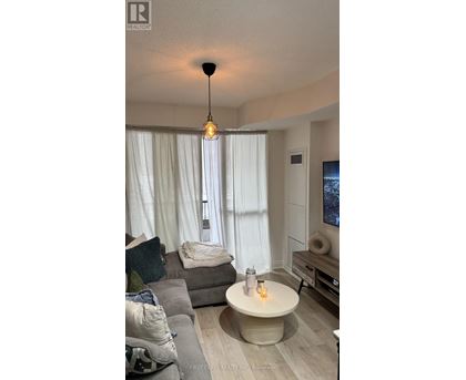 A living room with a grey couch and a round table with a lit candle on it.