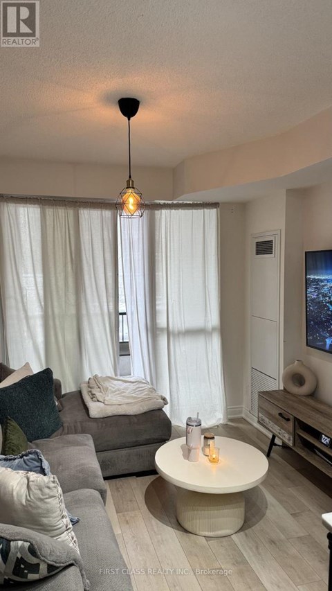 A living room with a grey couch and a round table with a lit candle on it.
