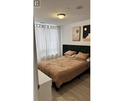 A bedroom with a bed, pillows, and pictures on the wall.