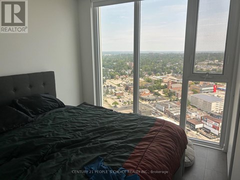 A bedroom with a large window overlooking a cityscape.
