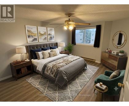 A bedroom with a large bed, a green armchair, and a ceiling fan.