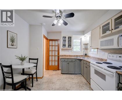 A kitchen with a white stove top oven and a white ceiling fan.