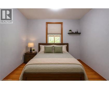 A bedroom with a bed, nightstand, and window.