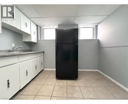 A black refrigerator in a kitchen with white cabinets.