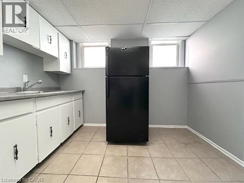 A black refrigerator in a kitchen with white cabinets.